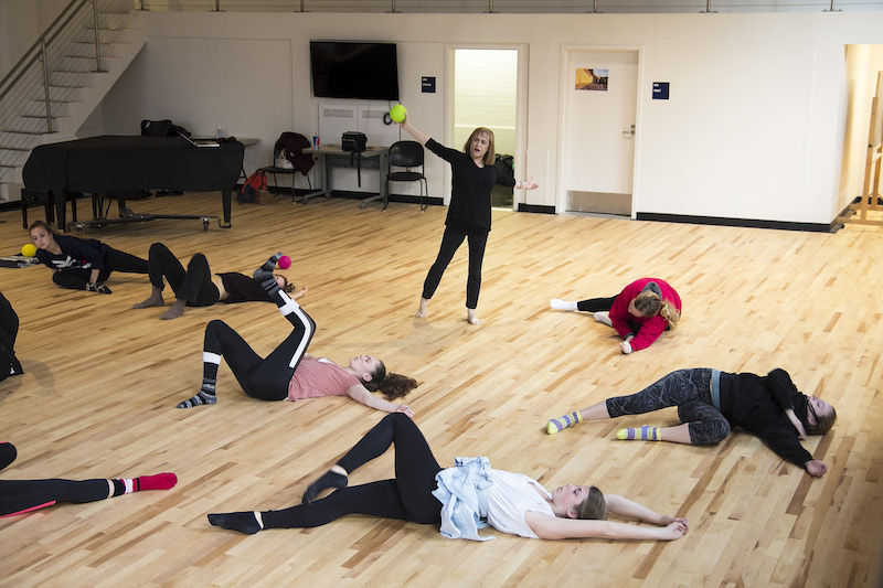 Certified Master Teacher Jill Green standing over a group of Kinetic Awareness Students in a large hall